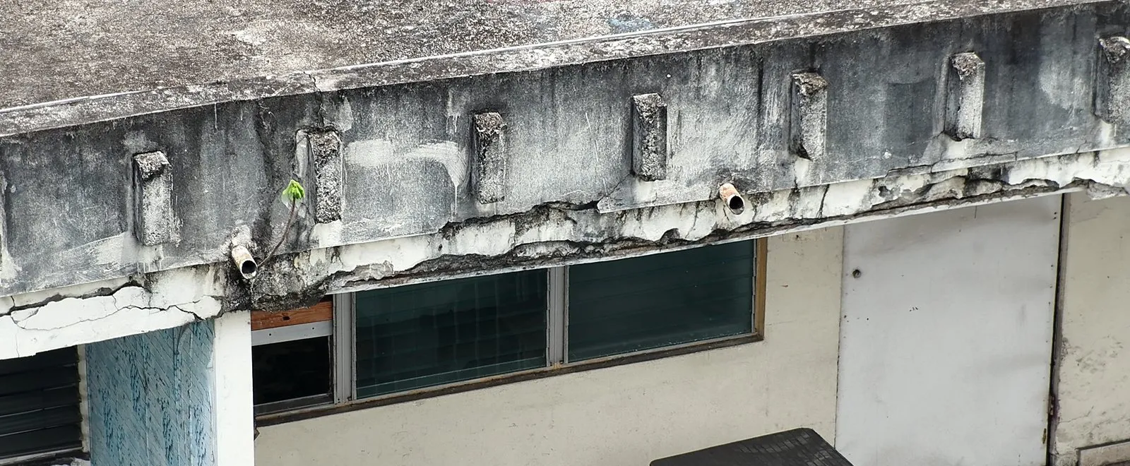 Viga de borde de un edificio con fisuras y desprendimiento de concreto, fotografiada con dron
